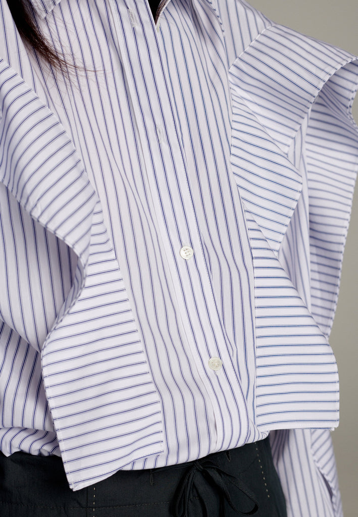 This cotton poplin shirt with a classic collar has six-hole buttons to adjust the neckline. Its cropped length accentuates the shirt's loose and open shape. Special detail with a panel of ruffles that creates a voluminous look to the garment.