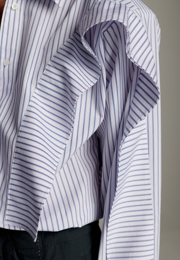 This cotton poplin shirt with a classic collar has six-hole buttons to adjust the neckline. Its cropped length accentuates the shirt's loose and open shape. Special detail with a panel of ruffles that creates a voluminous look to the garment.