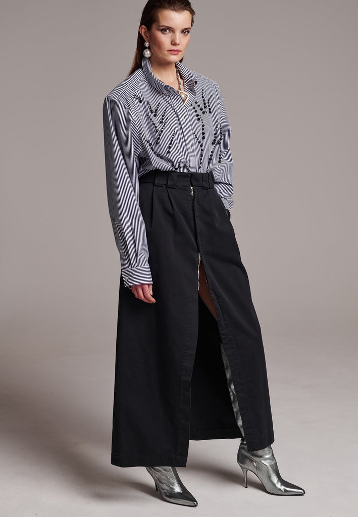 A deconstructed chino skirt featuring prominent front and back slits which create effortless movement within every step. Features pockets and big belt loops.