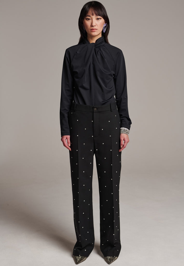 Discover unparalleled elegance with this structured bell-cut, perfectly tailored pant, adorned with striking Swarovski crystals that appear to be artfully scattered across the front. Designed by Frenken, this piece offers a slightly oversized fit, embodying a refined yet contemporary silhouette. Inspired by menswear, these trousers effortlessly blend sharp tailoring with a touch of glamour, ensuring a perfect fit and a standout addition to your wardrobe.