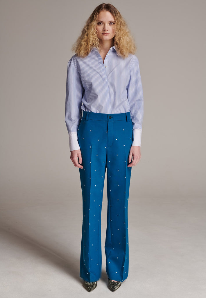 Discover unparalleled elegance with this structured bell-cut, perfectly tailored pant, adorned with striking Swarovski crystals that appear to be artfully scattered across the front. Designed by Frenken, this piece offers a slightly oversized fit, embodying a refined yet contemporary silhouette. Inspired by menswear, these trousers effortlessly blend sharp tailoring with a touch of glamour, ensuring a perfect fit and a standout addition to your wardrobe.