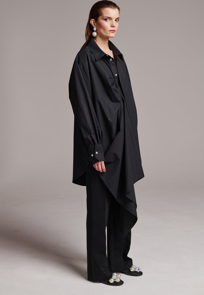 Oversized asymmetric shirt. Specially detailed with a long ruffle effect on one side. It has a button closure to adjust the neckline. 100% Cotton and with an oversized loose shape. Designed for a comfortable and unique fit. A timeless piece.