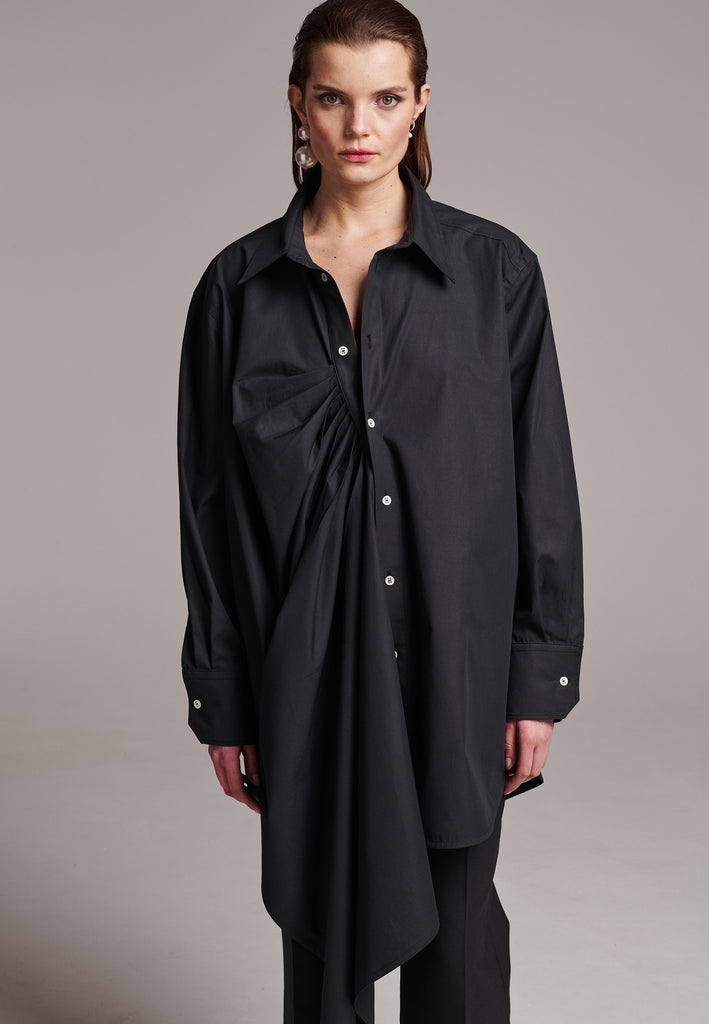 Oversized asymmetric shirt. Specially detailed with a long ruffle effect on one side. It has a button closure to adjust the neckline. 100% Cotton and with an oversized loose shape. Designed for a comfortable and unique fit. A timeless piece.