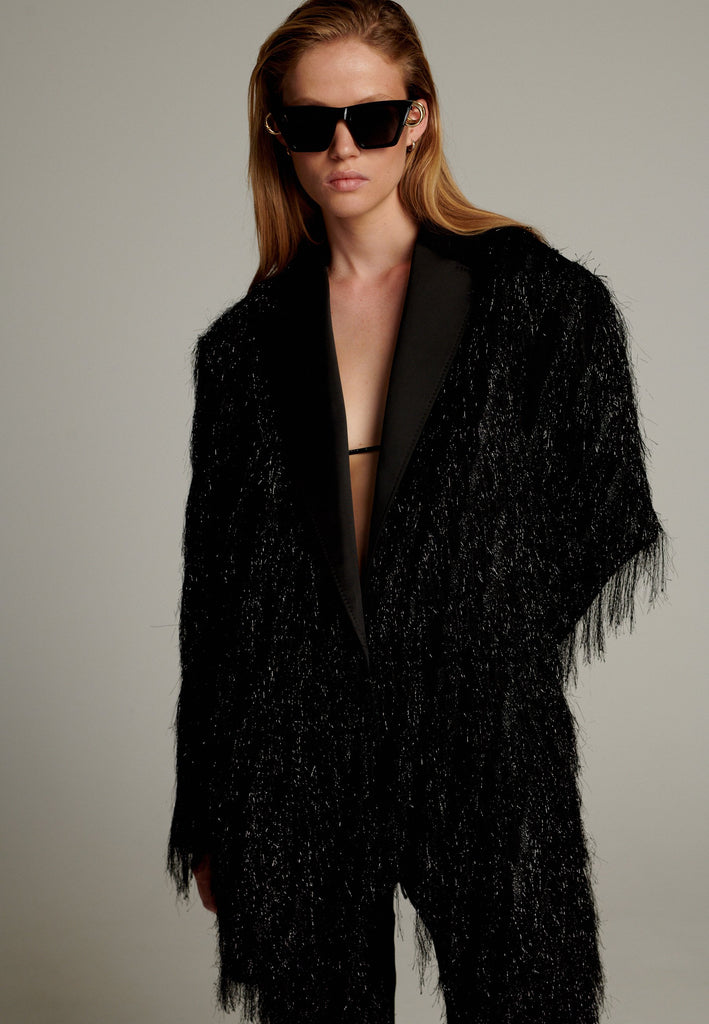 The pinnacle of sophistication with a bold touch. Crafted from elegant black fabric, it features an oversize cut that creates volume. Tinsel details add a modern and daring touch, perfect for glamorous evenings.