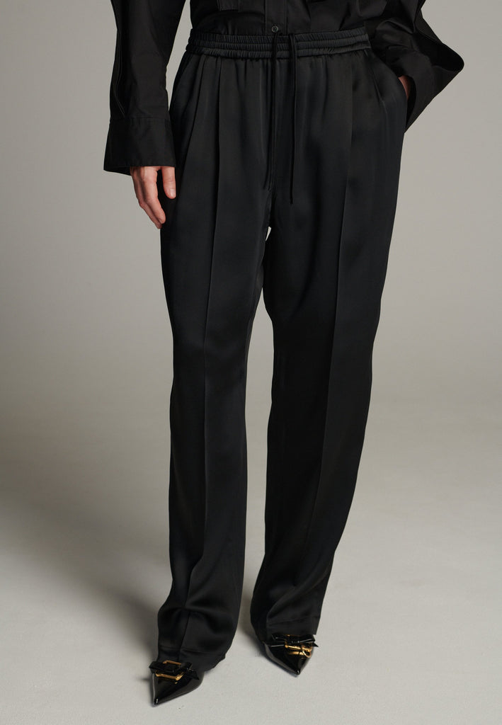 Crafted from smooth, high-quality crepe satin, they feature a relaxed, wide-leg silhouette inspired by traditional karate pants for a unique, contemporary twist. Designed with an elastic waistband, they offer a flexible, comfortable fit while maintaining a polished look. The elegant fabric drapes beautifully, creating fluid movement, making these trousers versatile enough to pair with both tailored blazers and casual tops.