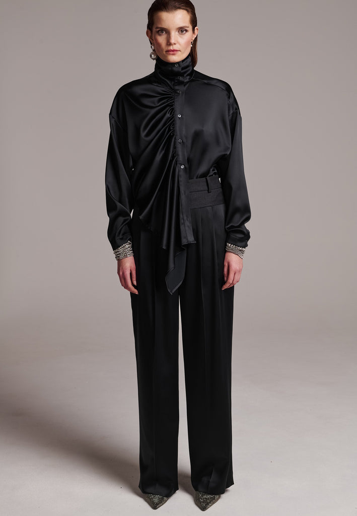 Elevate your wardrobe with this deconstructed molded top. Made in Portugal from fluid crepe satin. This gathered turtleneck top has dropped shoulders and an asymmetric dramatically gathered falling draped front panel that accentuates the loose, oversized shape. This versatile piece effortlessly transitions from day to night, making a sophisticated addition to any ensemble.