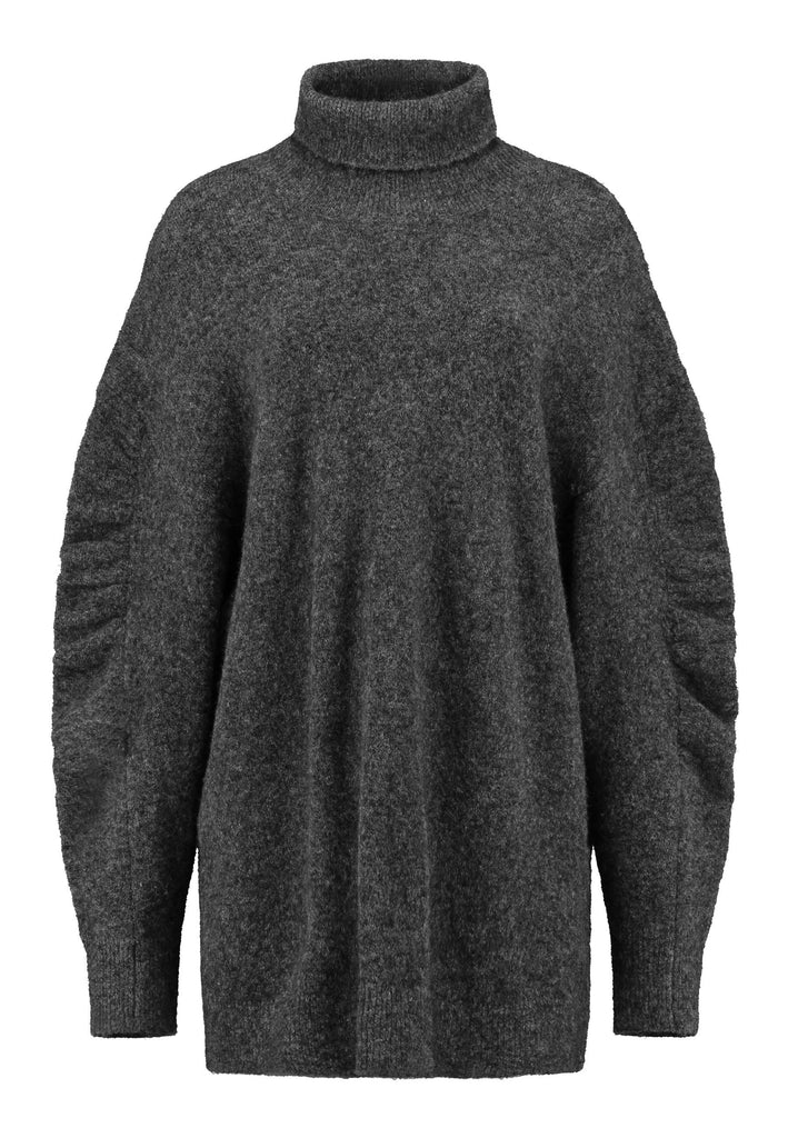 Stay warm and stylish with this oversized knitted sweater, crafted from luxurious virgin merino wool that gives a soft handle. Dropped shoulder seam detailed with gathering at the sleeves, it combines a cozy turtleneck with designer flair. This grey melange shade works especially well with black and grey tailoring and jeans. Designed for an oversized fit, cut to be worn very loose. Long in sleeves. This piece ensures you’ll stay snug and chic, even on the coldest days.