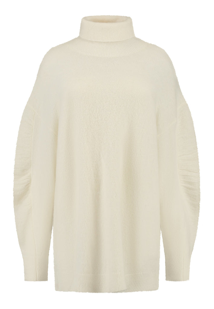 Stay warm and stylish with this oversized knitted sweater, crafted from luxurious virgin merino wool that gives a soft handle. Dropped shoulder seam detailed with gathering at the sleeves, it combines a cozy turtleneck with designer flair. The off-white shade works especially well with off-white tailoring and jeans. Designed for an oversized fit, cut to be worn very loose. Long in sleeves. This piece ensures you’ll stay snug and chic, even on the coldest days.