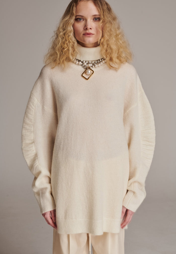 Stay warm and stylish with this oversized knitted sweater, crafted from luxurious virgin merino wool that gives a soft handle. Dropped shoulder seam detailed with gathering at the sleeves, it combines a cozy turtleneck with designer flair. The off-white shade works especially well with off-white tailoring and jeans. Designed for an oversized fit, cut to be worn very loose. Long in sleeves. This piece ensures you’ll stay snug and chic, even on the coldest days.