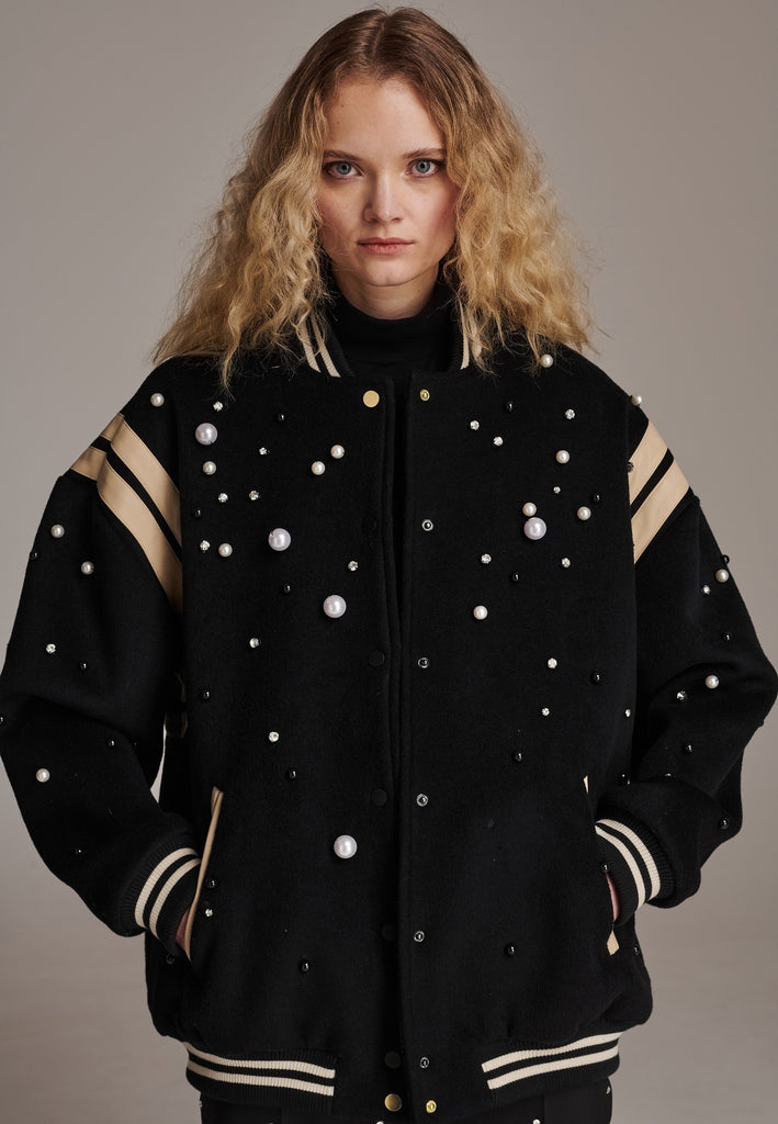 How cool is our oversized baseball jacket, finished with leather piping and adorned with faux pearls, meticulously hand-applied to create a stunning, galaxy-like effect. How would you wear it? Style it over a dress, pair it with a sleek tailored pant, or go for a bold look with oversized jeans. The possibilities are endless with this standout piece.