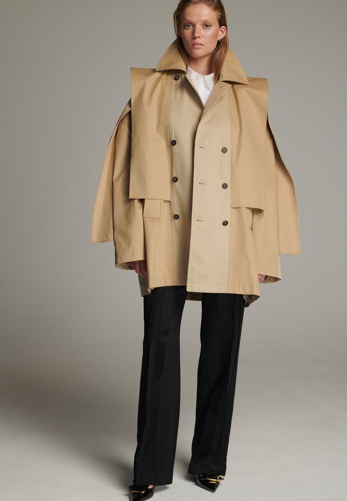 Inspired by a men's coat, FRENKEN offers a refined, contemporary twist on classic outerwear. Designed with dual-tone camel panels that create a subtle yet striking contrast, it exudes effortless sophistication. Featuring squared draped fabric, the coat showcases a modern, architectural design. Made from water-resistant cotton, it combines style, versatility, and functionality for everyday wear.