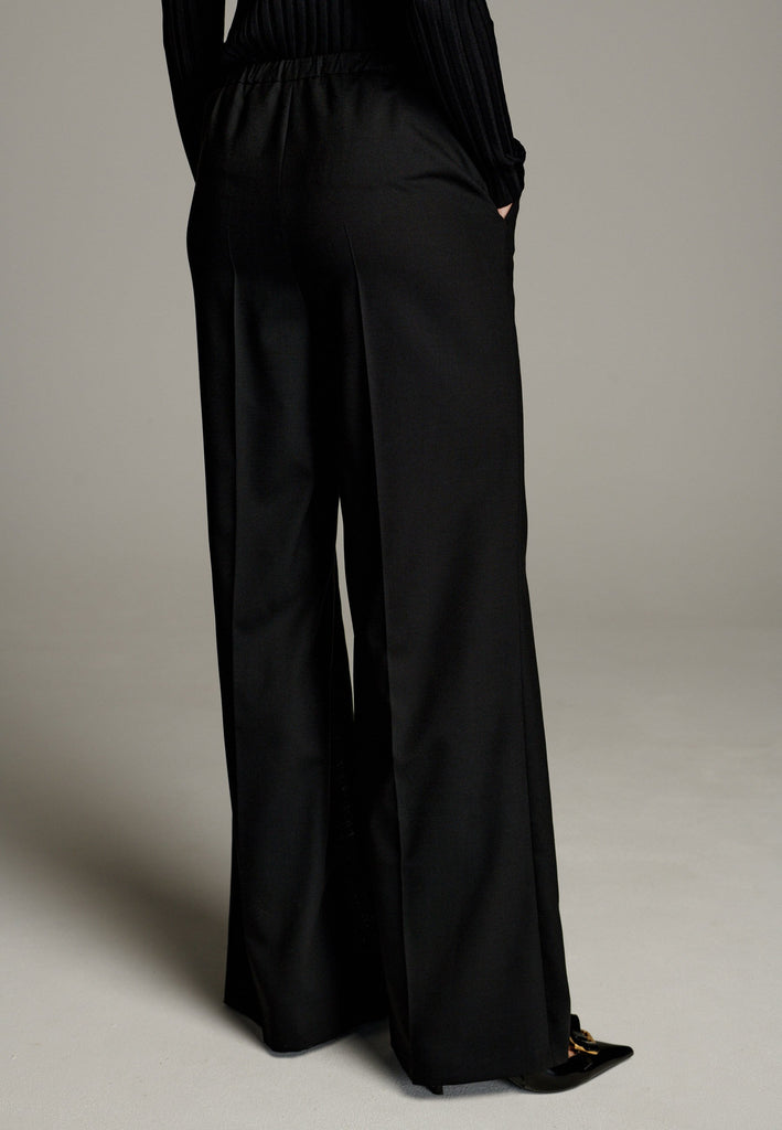 Made from a mix of polyester, wool, and elastane, they offer a soft, stretchy feel with a flattering drape. Designed with an elastic waistband, these pants ensure all-day comfort and a flexible fit. Featuring invisible zipper slits on both legs, they add a modern, stylish edge while allowing for ease of movement.