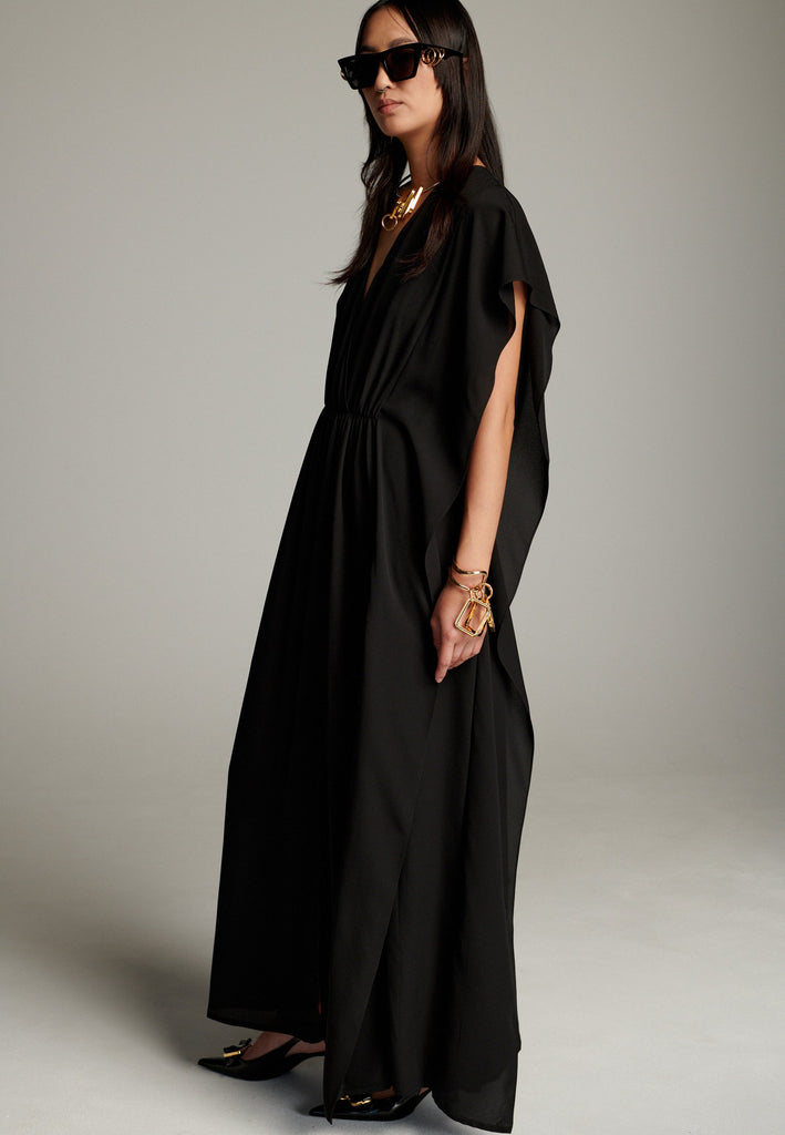 This dress features a flowing and elegant design in a black hue, crafted from lightweight silk georgette. The V-neckline and cinched waist create a flattering silhouette, while the loose, cape-like sleeves add a touch of modern sophistication. Perfect for both formal occasions and chic casual settings, it exudes timeless elegance and versatility.