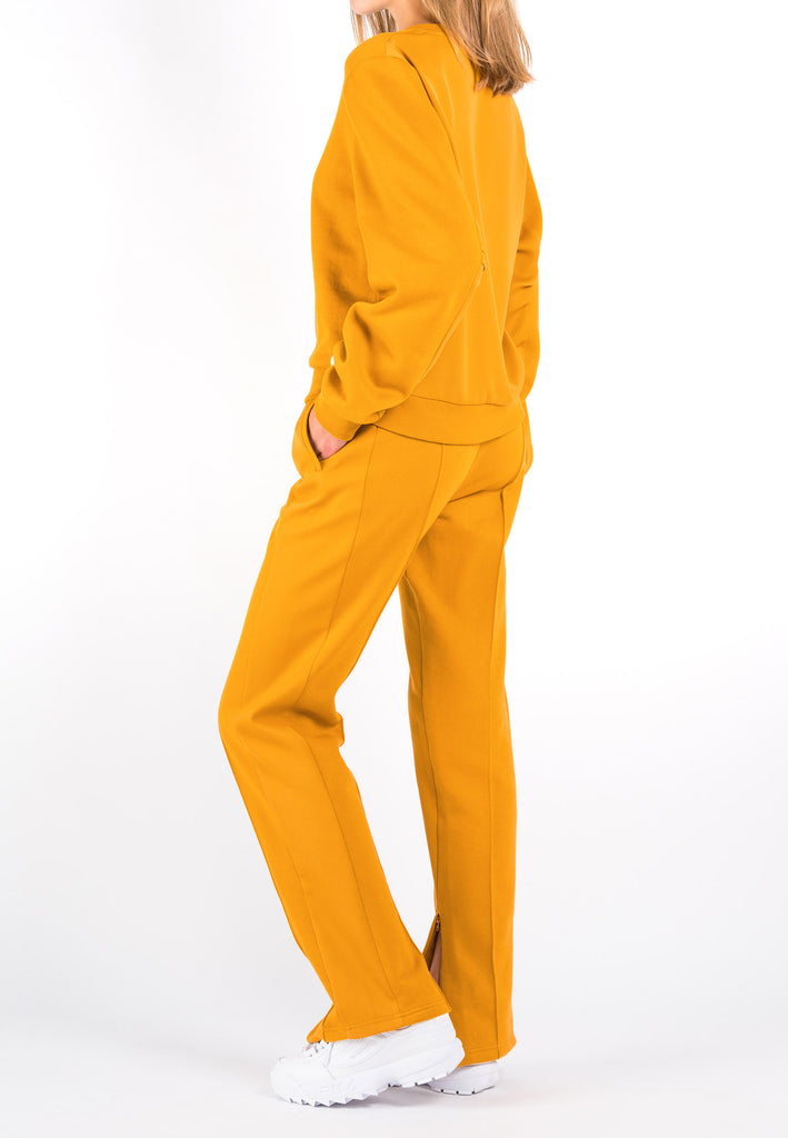 Equal | Pants | Mandarin. Jogger pants with an elastic waistband, satin-like side strip and zipper detail at ankle. Model wears a size 36.