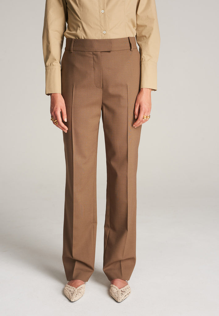 FRENKEN Line camel trouser made of fine wool with elastane for a touch of stretch and added comfort. The shape is accentuated by carefully pressed creases for the perfect fit. With belt loops, concealed zipper, and button and pockets. Also available in pink.