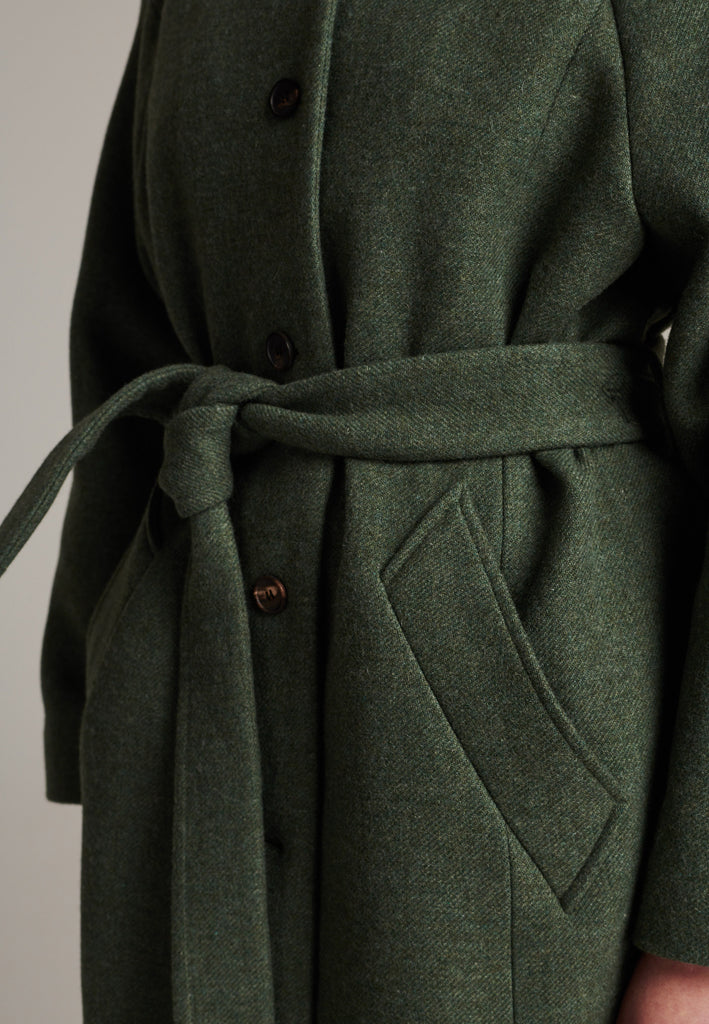 Oversized relaxed-fit coat in green melange cut from a recycled soft wool blend, fully lined with satin. It comes with a coordinating belt to temper the loose fit and to cinch to the waistline.