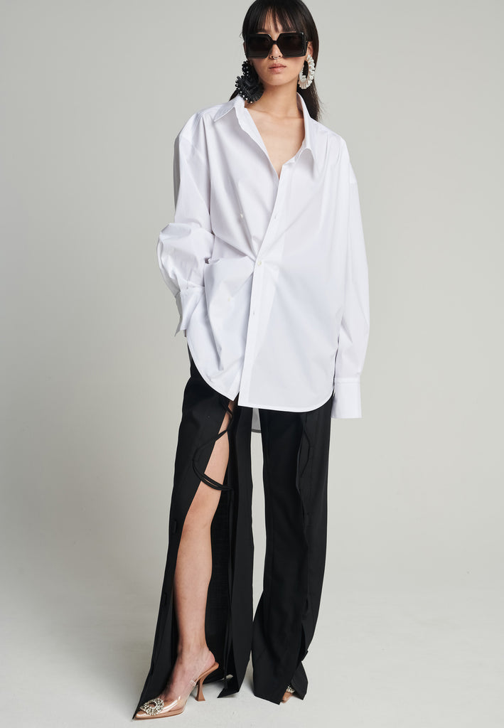 Menswear-inspired wrap-shirt in white. Features a second row of buttons, wear it normally or asymmetrically. 2 in 1. Fits oversize.