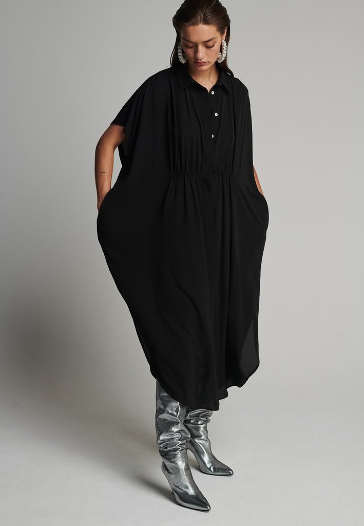 Silk midi dress in black. Features a short sleeve, front and back wrinkled effect, and an elastic waistband. Fits oversize.