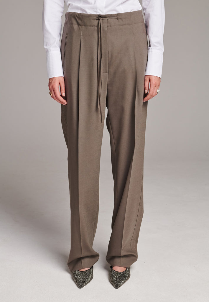 Mid waist wide-leg trousers. Detailed with waisted strings, back pockets and pressed creases.